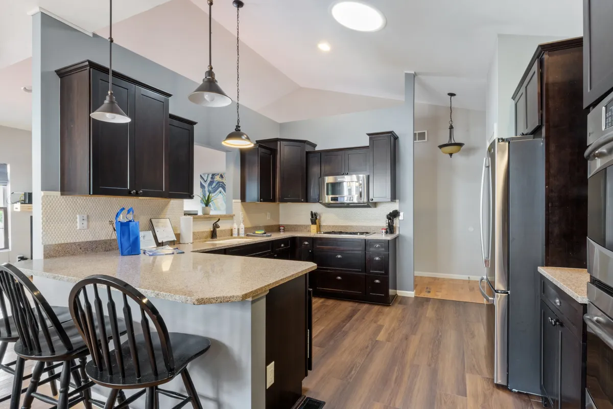 A modern kitchen with granite countertops, dark cabinetry, bar stools, and stainless steel appliances. The open layout supports both cooking and socializing, making it easy for guests to gather and interact.