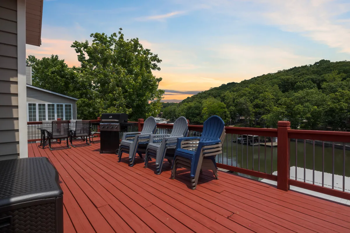 An inviting deck setup with comfortable chairs, a grill, and a scenic view of the water beyond. The scene suggests a blend of relaxation and socializing by the lake, ideal for unwinding after a day on the water or hosting lakeside gatherings.