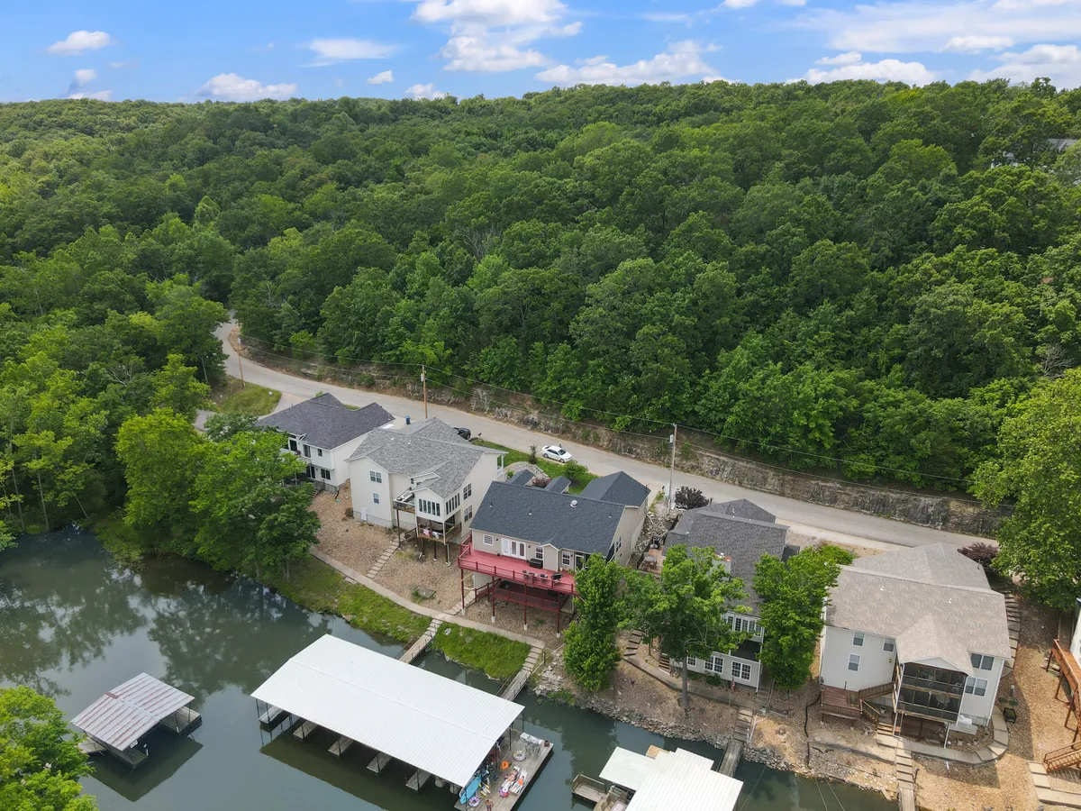 A peaceful exterior scene showcasing homes by the lake with a dock extending into the water, surrounded by trees and calm waters. The dock invites boating, fishing, and lakeside relaxation, reinforcing the lakefront lifestyle.