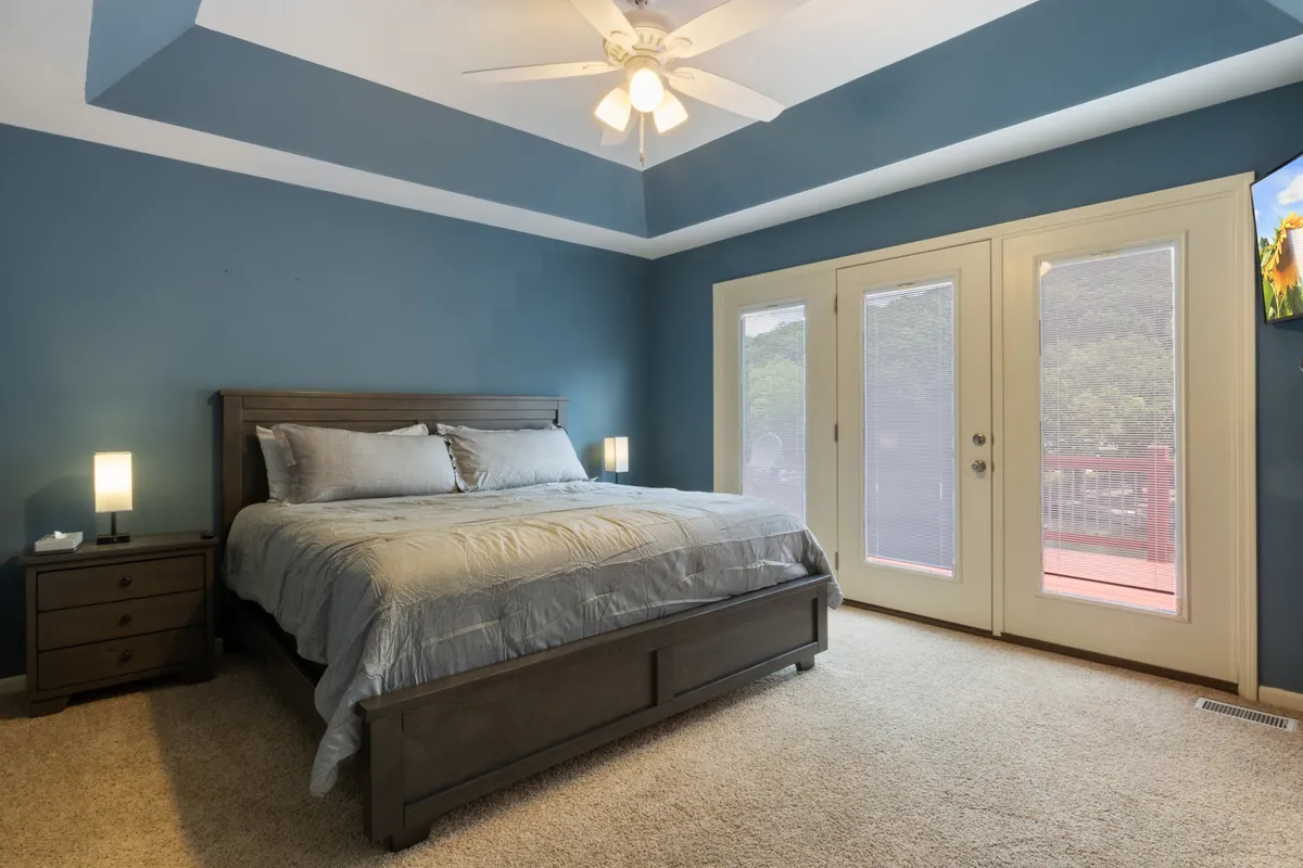 This image captures a bedroom featuring a bed positioned near large sliding doors that open to a balcony, inviting natural light and offering a subtle glimpse of the outdoors. The tranquil mood and inviting setup hint at the possibilities of starting a day with views of the surrounding area before heading out to explore.