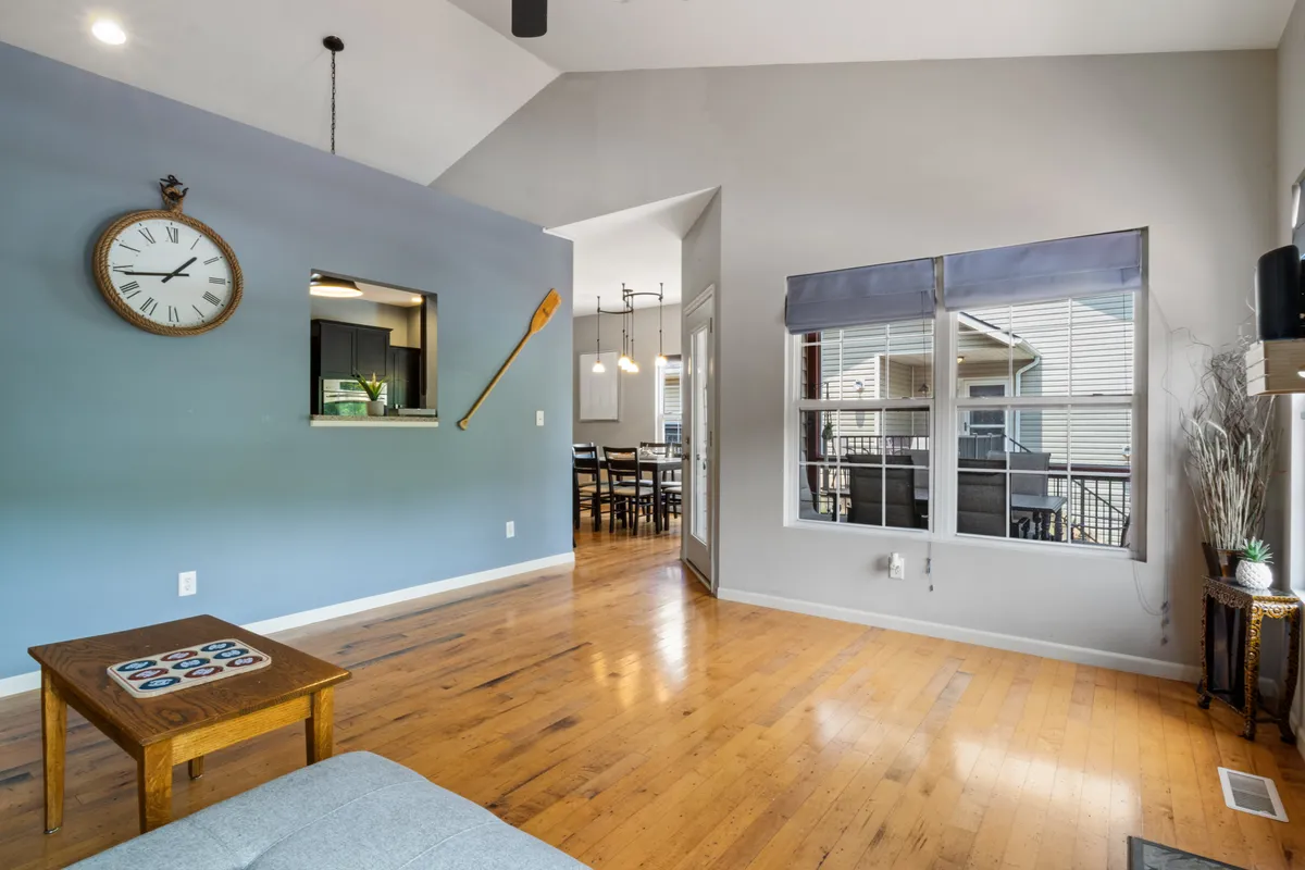 A welcoming dining space with a large wooden table set for a meal, visible through a doorway. Nautical decor and a prominent wall clock add personality, while the spaciousness suggests ample room for shared meals and celebrations.
