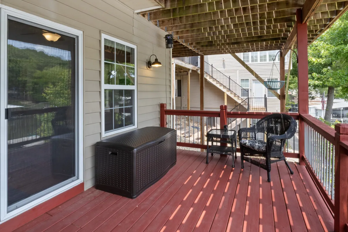 A serene exterior deck featuring comfortable seating with a storage bench and railings, surrounded by natural greenery. The area offers a tranquil space ideal for enjoying the peaceful lakeside atmosphere and connecting with the outdoors.