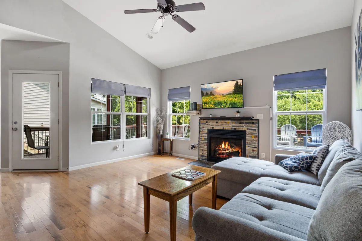 A welcoming living room with a plush sofa, a central coffee table, a fireplace, large windows letting in ample natural light, and a smart television. The space invites guests to relax, socialize, or enjoy entertainment in a cozy yet upscale setting.