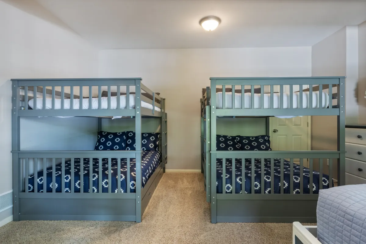 A family-friendly bedroom featuring bunk beds and soft linens on a cozy carpeted floor. The space feels playful yet restful, ideal for families or groups, and lends itself to late-night chats and sleepovers.