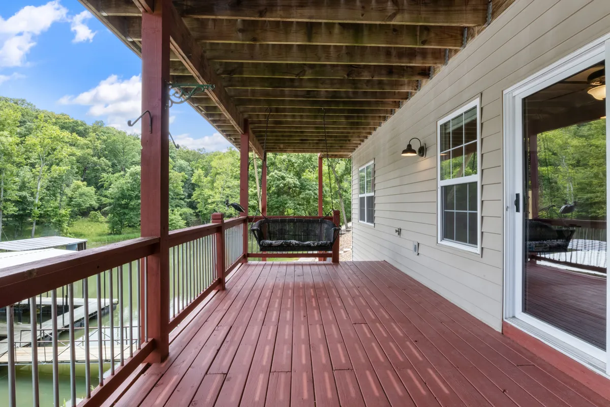 A scenic wooden deck with a cozy swing seat, surrounded by trees and looking out over the sparkling water. The tranquil scene suggests both private relaxation and shared moments, blending natural beauty with the comfort of well-designed outdoor spaces.